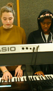 Two students practice playing the keyboard together in Band Class at Bayhill High School